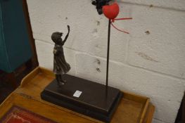 In the manner of Banksy, a bronze model of a girl waving at a heart shaped balloon.