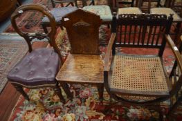 A cane seated elbow chair, an oak hall chair and a Victorian dining chair.