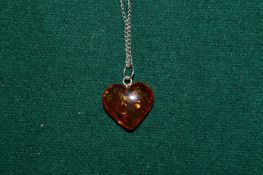 An amber heart shaped pendant with silver chain.
