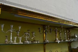 A collection of plated candlesticks and candelabra.