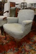 A small upholstered armchair on carved cabriole legs with paw feet.