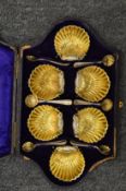 A good cased set of six shell shaped silver plated salts with spoons.