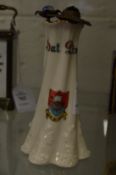 A crested china hat pin stand with three hat pins.