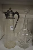 A cut glass claret jug with metal mounts together with a glass decanter.