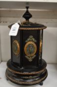 A Victorian black lacquer musical revolving cigar caddy with decorative mounts.