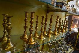 Eight pairs of brass candlesticks and two odd candlesticks.