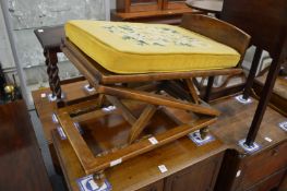 An adjustable gout stool with cane work foot rest and needlework cushion.