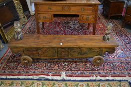 An Indonesian carved wood wheeled stand or bench mounted with carved and painted figures.