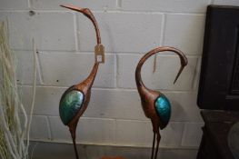 A pair of painted metal models of storks.