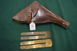 A leather pistol holster and pair of brass button polishing guards.