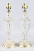 A PAIR OF CRYSTAL GLASS URN SHAPED LAMPS on circular bases. 20ins high.