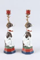 A PAIR OF SEVRES DESIGN PORCELAIN DOG CANDLESTICKS on hexagonal bases. 14ins high.