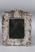 A SILVER EMBOSSED PHOTOGRAPH FRAME REPOUSSE WITH CUPIDS. 8.5ins x 6.5ins.