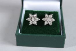 A PAIR OF 9CT AND SEVEN DIAMOND DAISY CLUSTER STUDS.