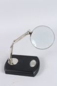 A CHROME MAGNIFYING GLASS on a stand.