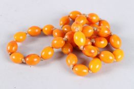 A STRING OF CHERRY AMBER BEADS. 26ins long.