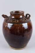 AN ISLAMIC BROWN GLAZE VASE with small handle and spout. 10ins high.