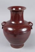 A CHINESE BROWN POTTERY VASE with lion ring handles. Impressed mark. 10ins high.