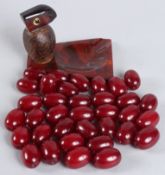A YZ DUNHILL STYLE BIRD ASHTRAY with Bakelite base and cherry amber beak, with loose red beads.