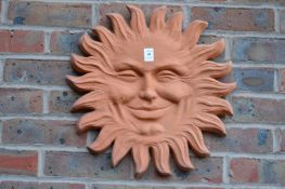 A terracotta sunburst wall plaque.