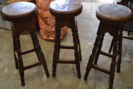 A set of three oak bar stools and a chair.