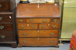 A George III oak bureau, the fall flap enclosing a fitted interior above three drawers, two