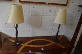 A pair of small bronze table lamps with shades.