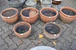 A set of four terracotta planters and a pair of matching smaller planters.