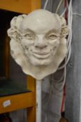 An unusual pottery model of a clowns head mounted on a pole.