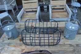 Two galvanised watering cans and a pair of wrought iron wall mounted plant holders.