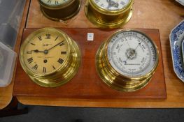 Ship style brass clock and aneroid barometer mounted on a mahogany board.