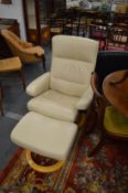 A cream leather upholstered reclining swivel armchair with matching stool.