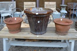 A large glazed terracotta planter and a pair of terracotta planters.