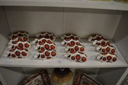 A collection of sixteen Royal Crown Derby pigs with floral painted bodies.