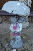 Garden ornament modelled as two children under an umbrella.