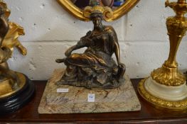 A patinated brass figure of a seated classical female mounted on a stepped marble base.