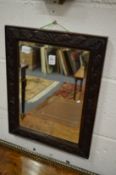 A small mirror with carved oak frame.