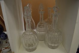 A group of five cut glass decanters.