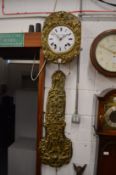 A Continental wall clock with embossed brass decoration to the dial and pendulum.