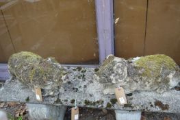 A pair of reconstituted stone weathered garden ornaments modelled as reclining pigs.