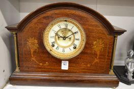 A mahogany mantel clock with visible escapement.