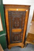 An oak standing corner cupboard with carved panel door.