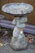 A reconstituted stone bird bath with cherub support.