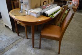 A teak extending dining table with four similar chairs.