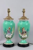 A PAIR OF VICTORIAN PORCELAIN LAMPS painted with a young girl and flowers, on circular wooden bases.