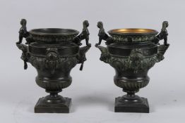 A GOOD PAIR OF GRAND TOUR BRONZE TWO HANDLED URNS with Egyptian handles and masks, 8ins high.
