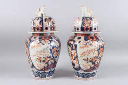 A GOOD PAIR OF IMARI VASES AND COVERS with kylin handles, the body painted in red and blue. 44cm