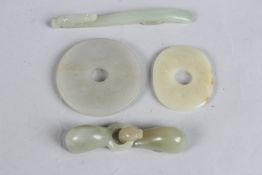 A COLLECTION OF FOUR CHINESE JADE ITEMS to include two disc pendants and two belt buckles