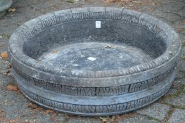 A barrel style shallow circular composite stone planter.