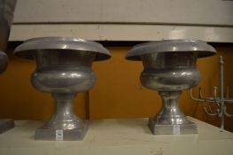 A pair of urn shaped aluminium vases.